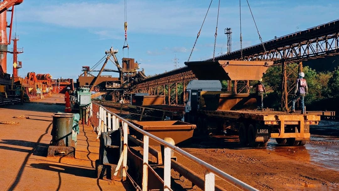 Maniobra de carga con grúa sobre camión plataforma en muelle portuario