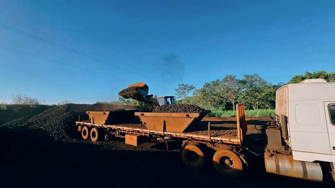 Cargador frontal llenando bateas de material a granel sobre camión plataforma