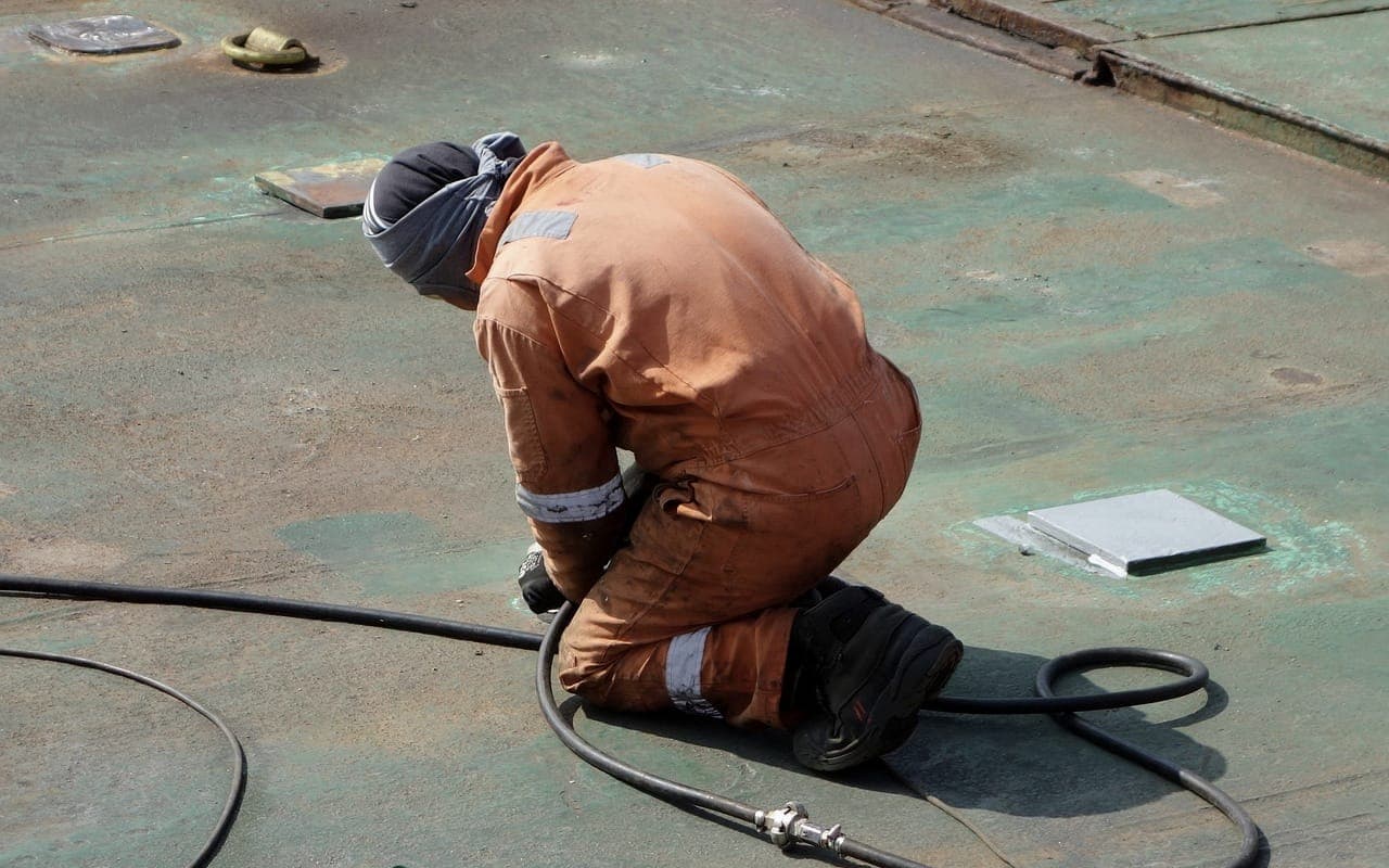 Técnico con traje de protección trabajando sobre una cubierta industrial